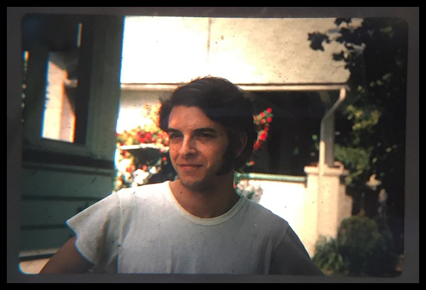 young Dr.
              Lorenzo in a white T-shirt with long sideburns